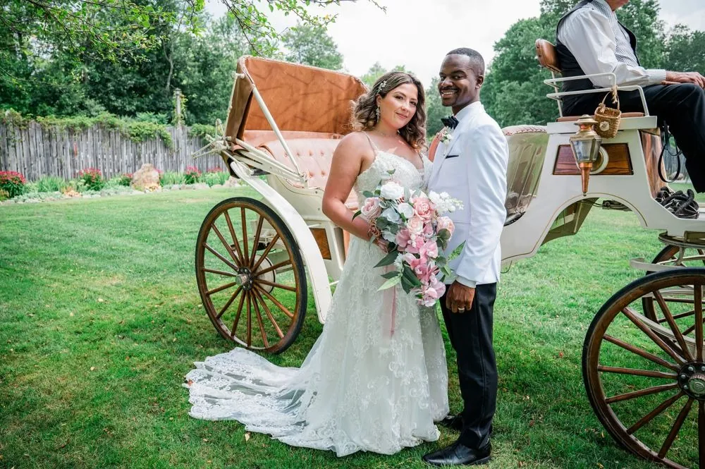 Jhamar and Tifany pose beside a white horse-drawn carriage on the lawn