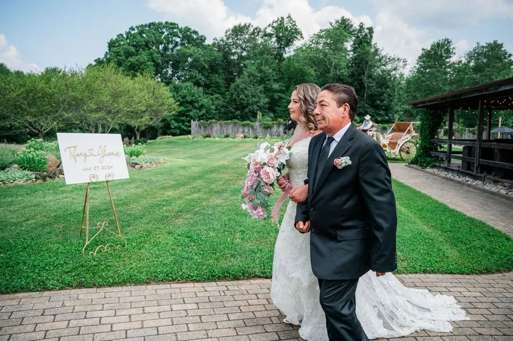 The bride walks the brick aisle on a man's arm toward the arch