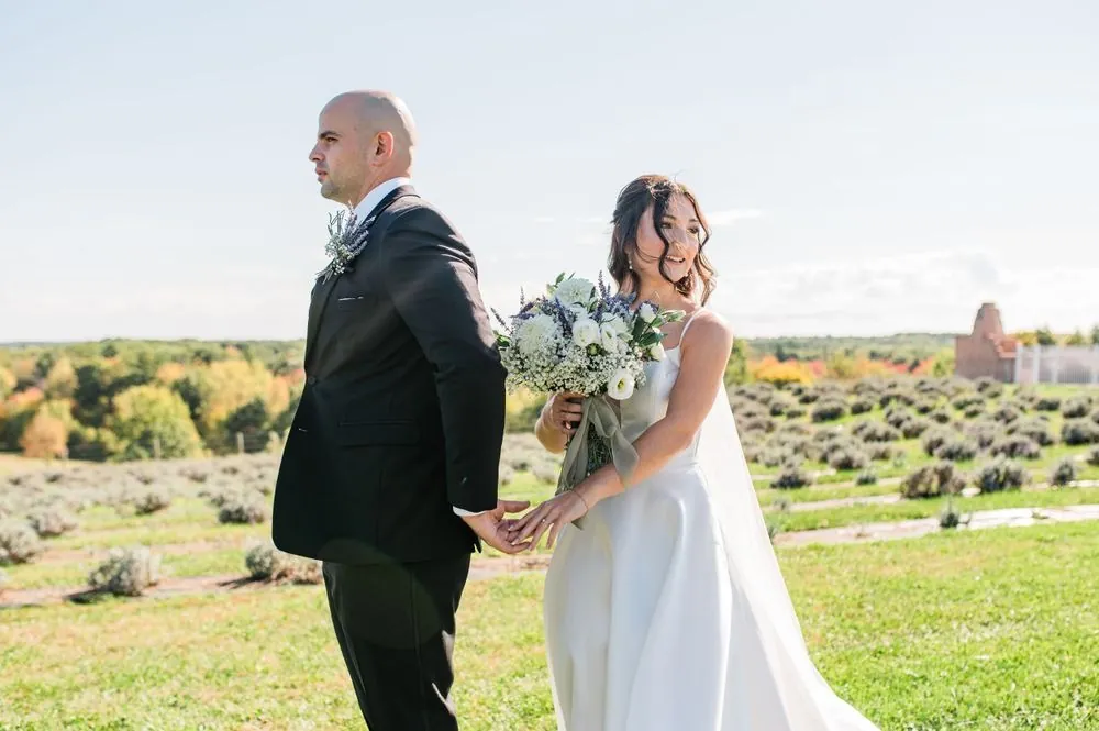 Kailey and Patrick hold hands back to back among lavender rows and early fall trees