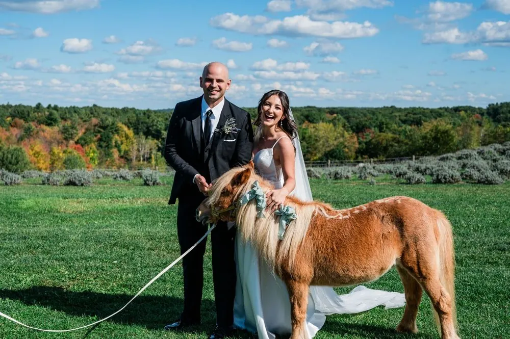 Kailey and Patrick stand on the lawn with a shaggy chestnut pony above the valley