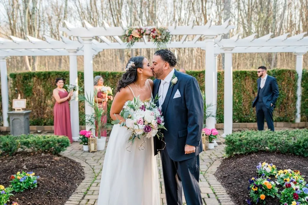 Karla and Carlos share a kiss on the garden path after the ceremony