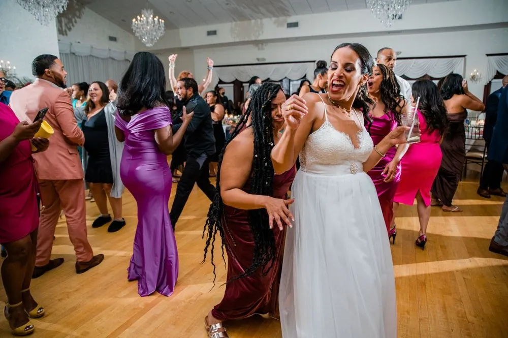 The bride dances in a crowd of guests on the reception floor, laughing