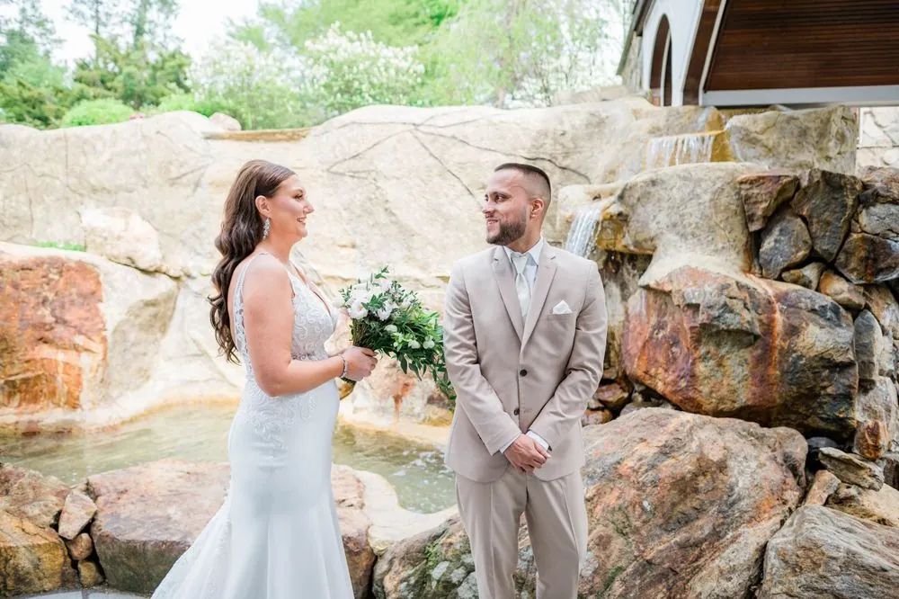 Kasey and Derek face each other on the rocks beside a small waterfall