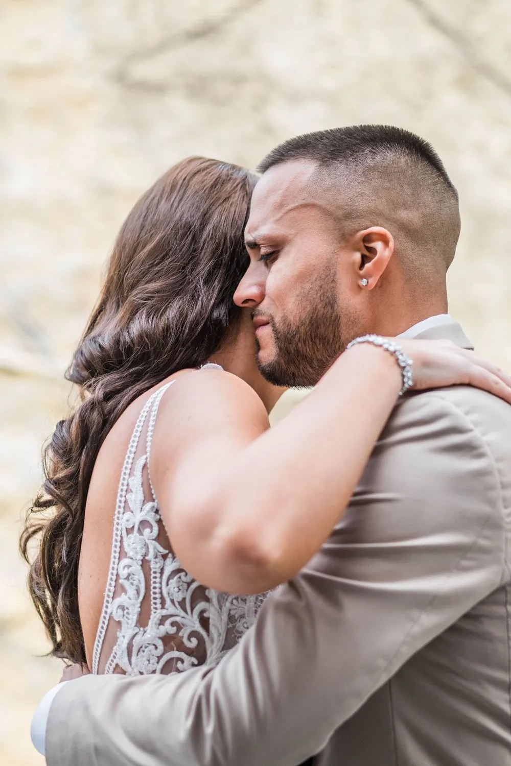 The bride hugs the groom tightly, her cheek against his shoulder