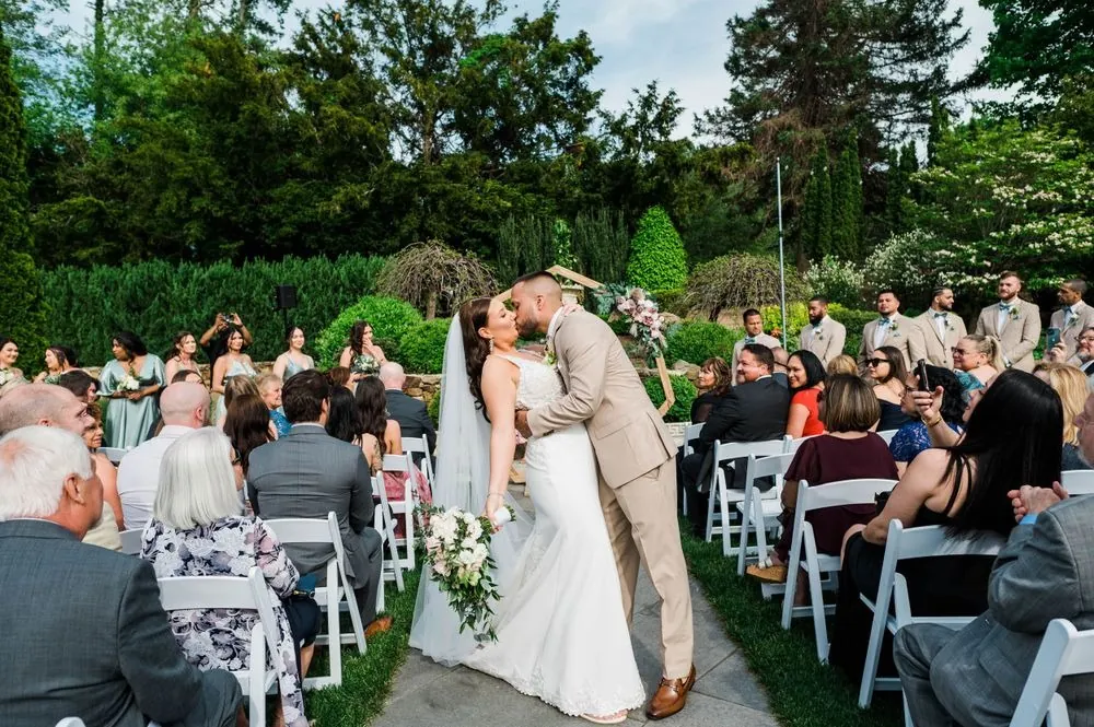 Kasey and Derek kiss at the end of the aisle between rows of guests