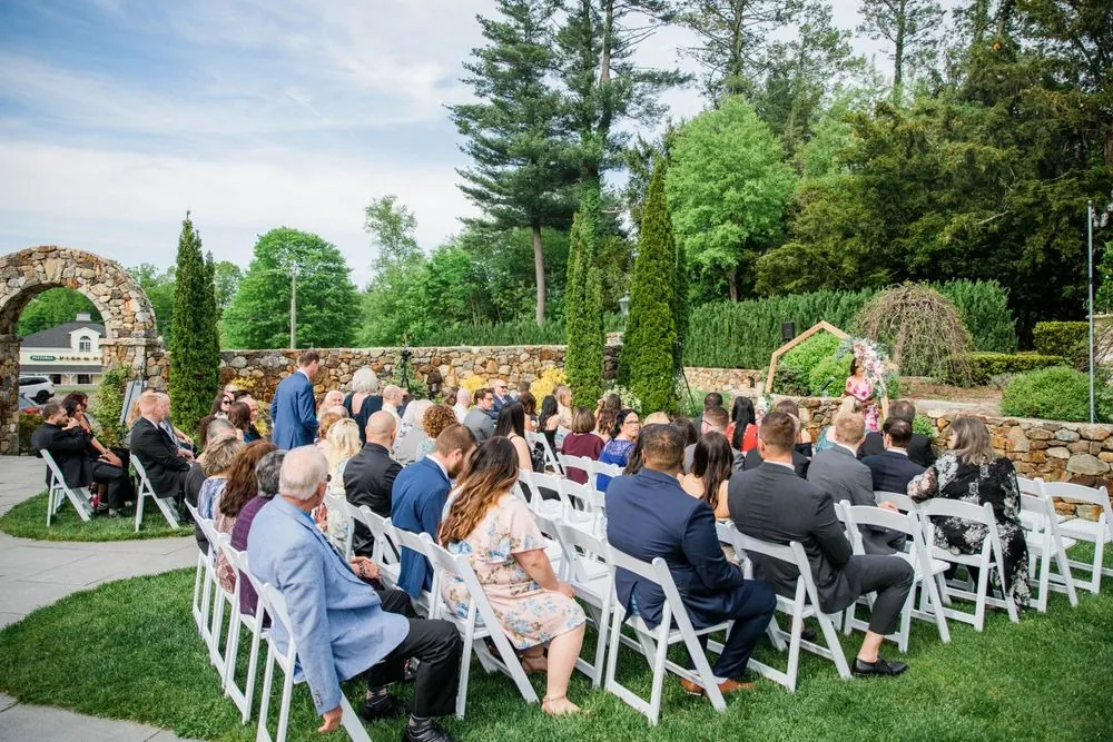 Wide view of the garden ceremony with guests seated on the lawn
