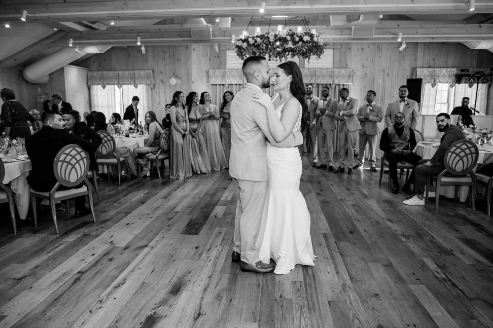 Black and white of the first dance with guests watching around the floor
