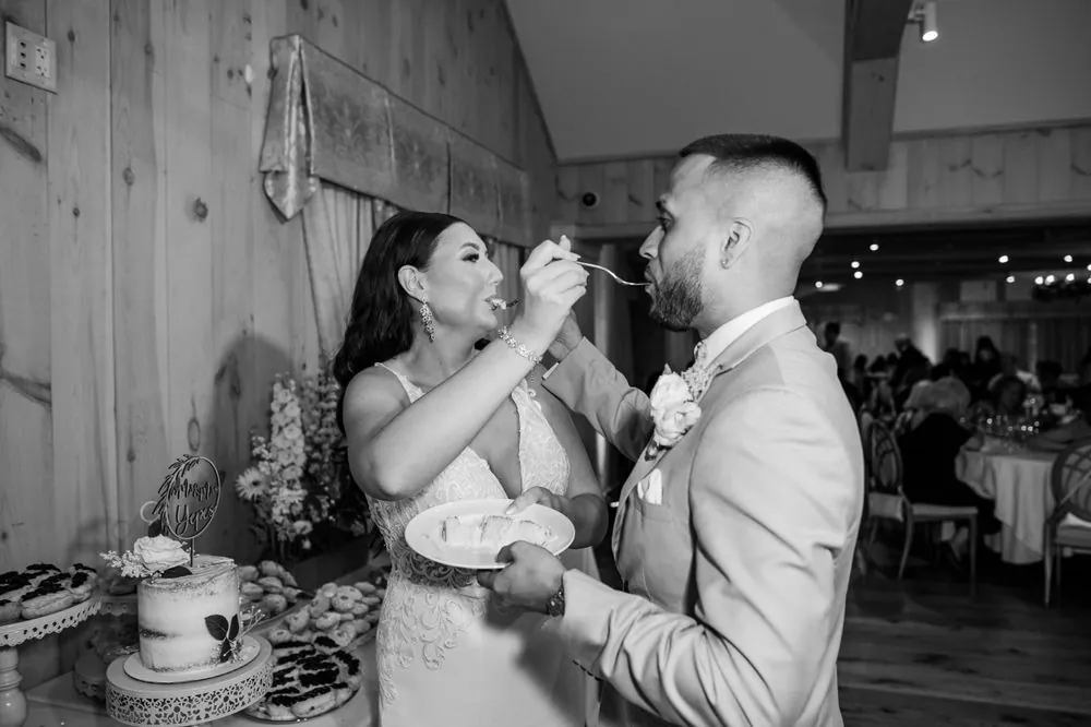 Black and white of the bride feeding the groom a bite of cake