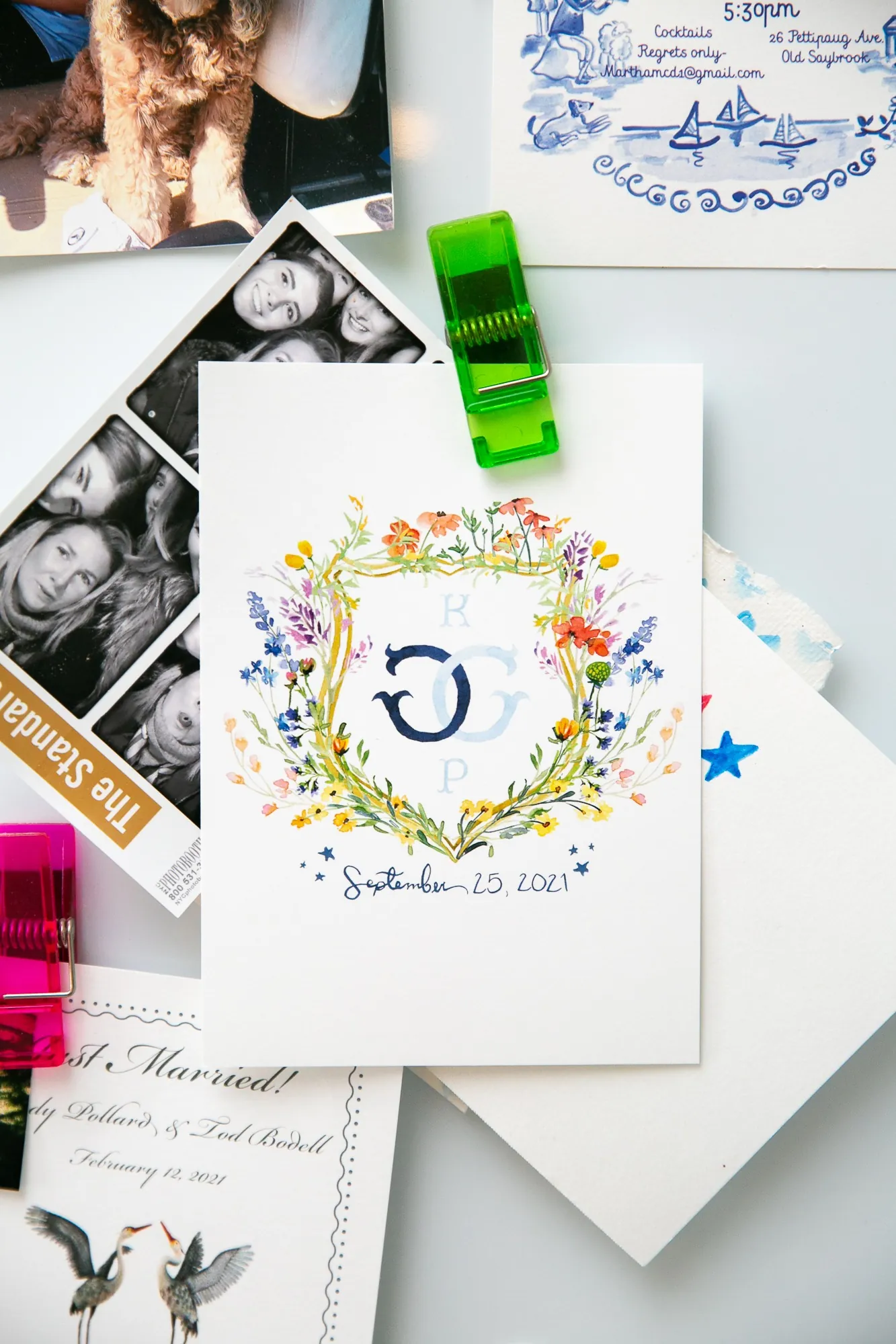 An invitation suite with a painted crest, blue and white motifs and a green ribbon