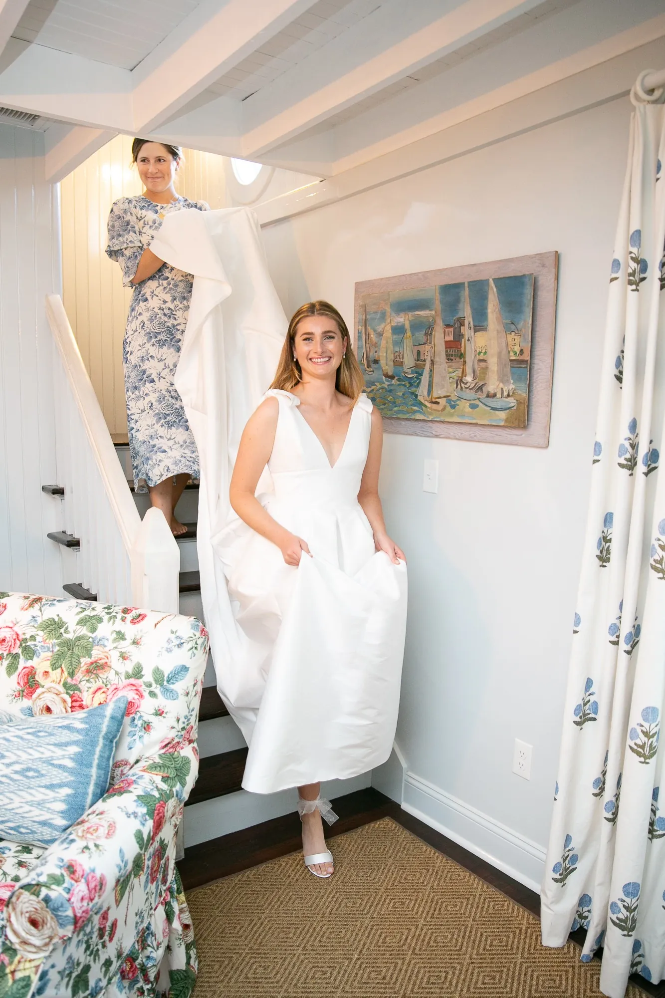The bride comes down a narrow white staircase in her gown