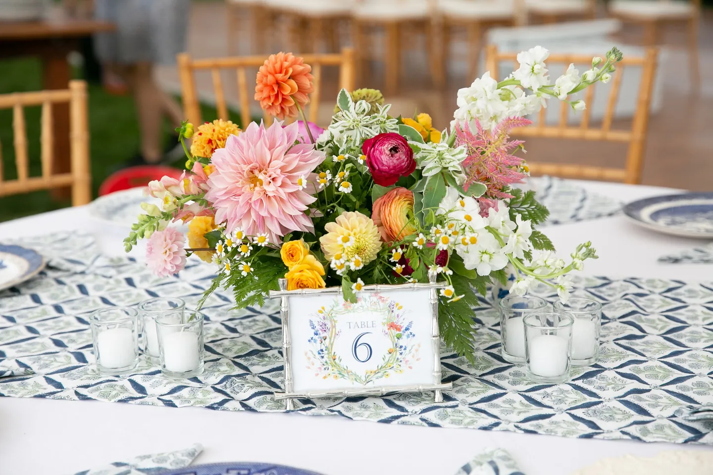 Table 6 card among orange dahlias and pink blooms on a blue patterned tablecloth