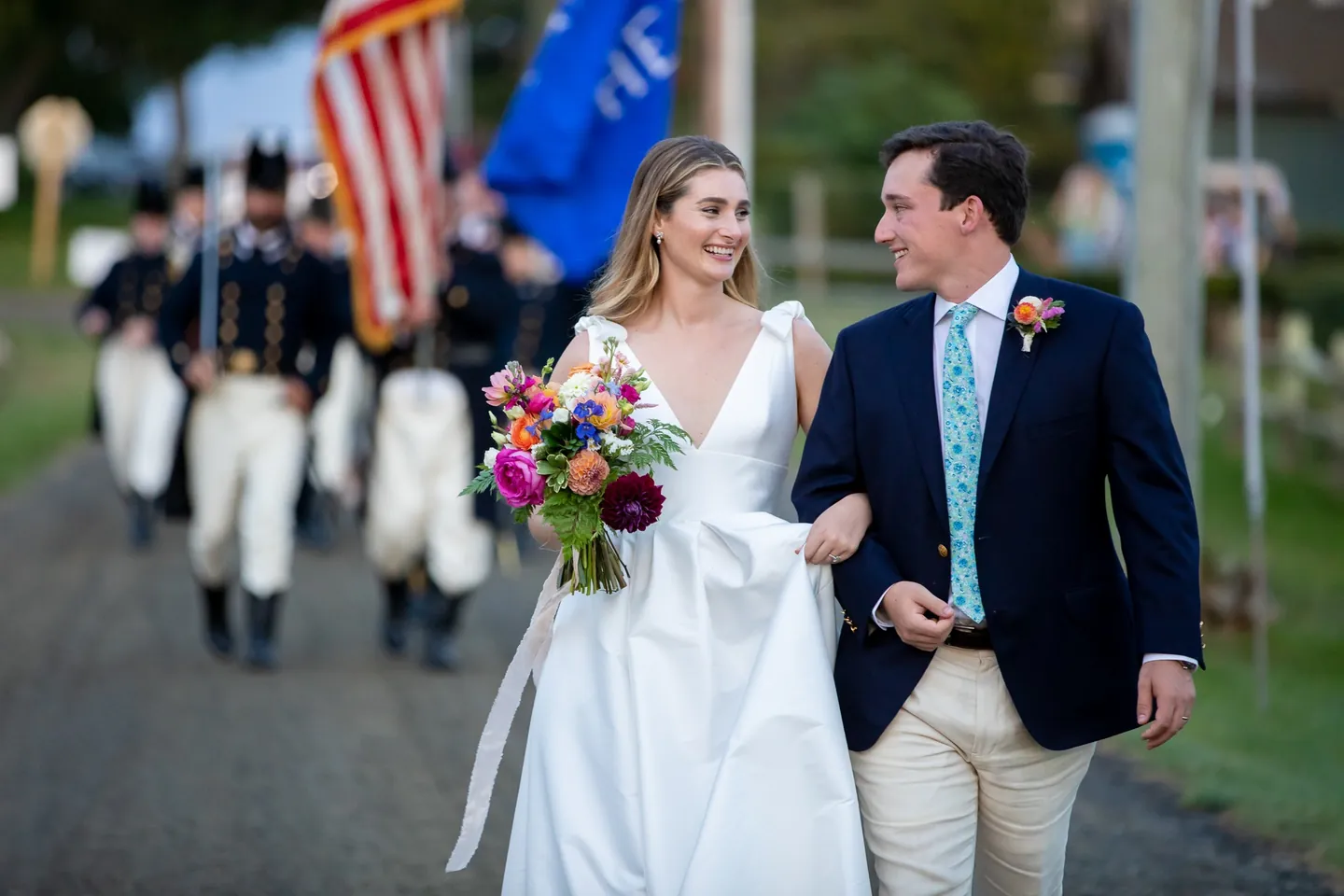 Kate and Parker walk arm in arm, smiling, as the fife and drum corps marches behind them
