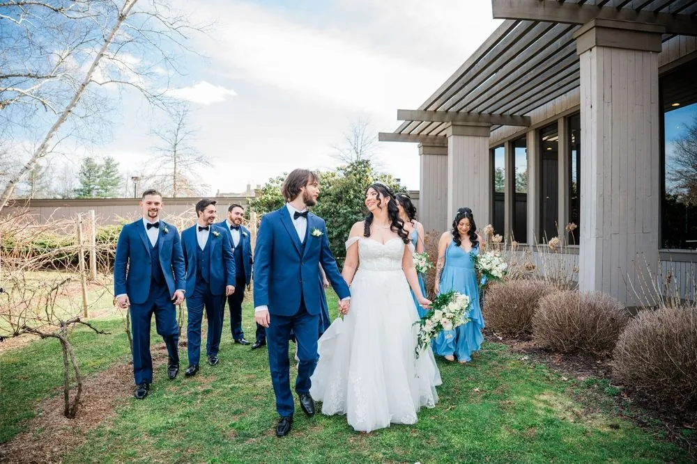 Monica and Kevin walk the lawn hand in hand with the wedding party behind them