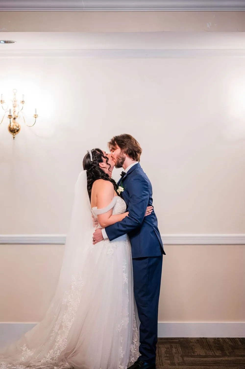 Monica and Kevin share their first kiss against a pale wall
