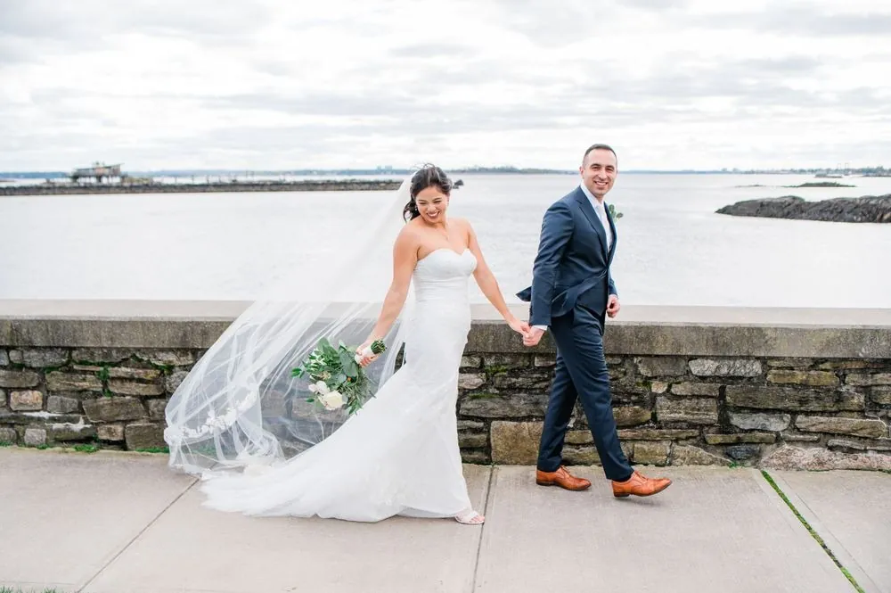 Kim leads Fabiano by the hand along the stone seawall, her veil streaming behind