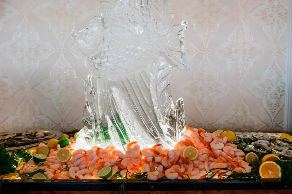 Shrimp and citrus piled beneath an ice sculpture of a leaping fish