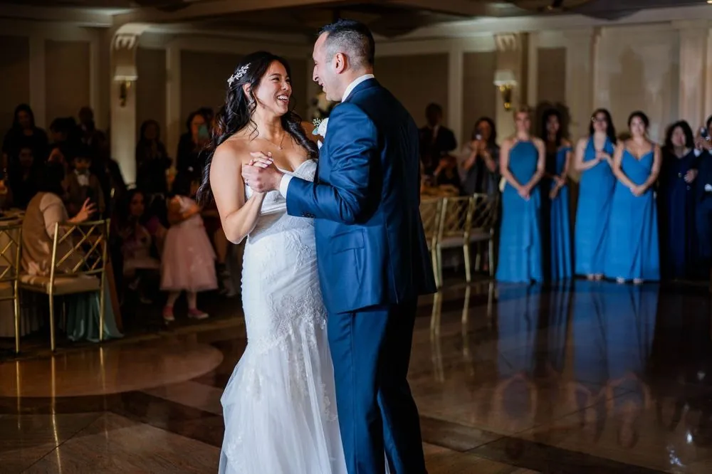 First dance in the ballroom as bridesmaids in blue watch from the edge