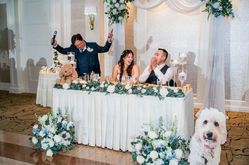 Guests cheer at the head table beside a cutout of a curly goldendoodle