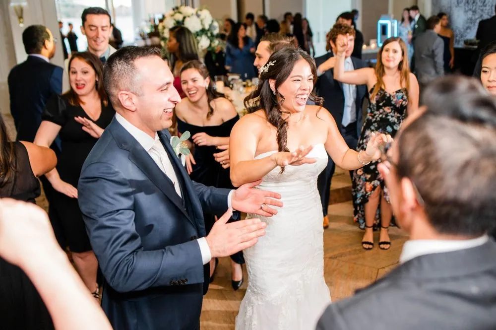 Kim and Fabiano dance and clap in the middle of a crowded ballroom floor