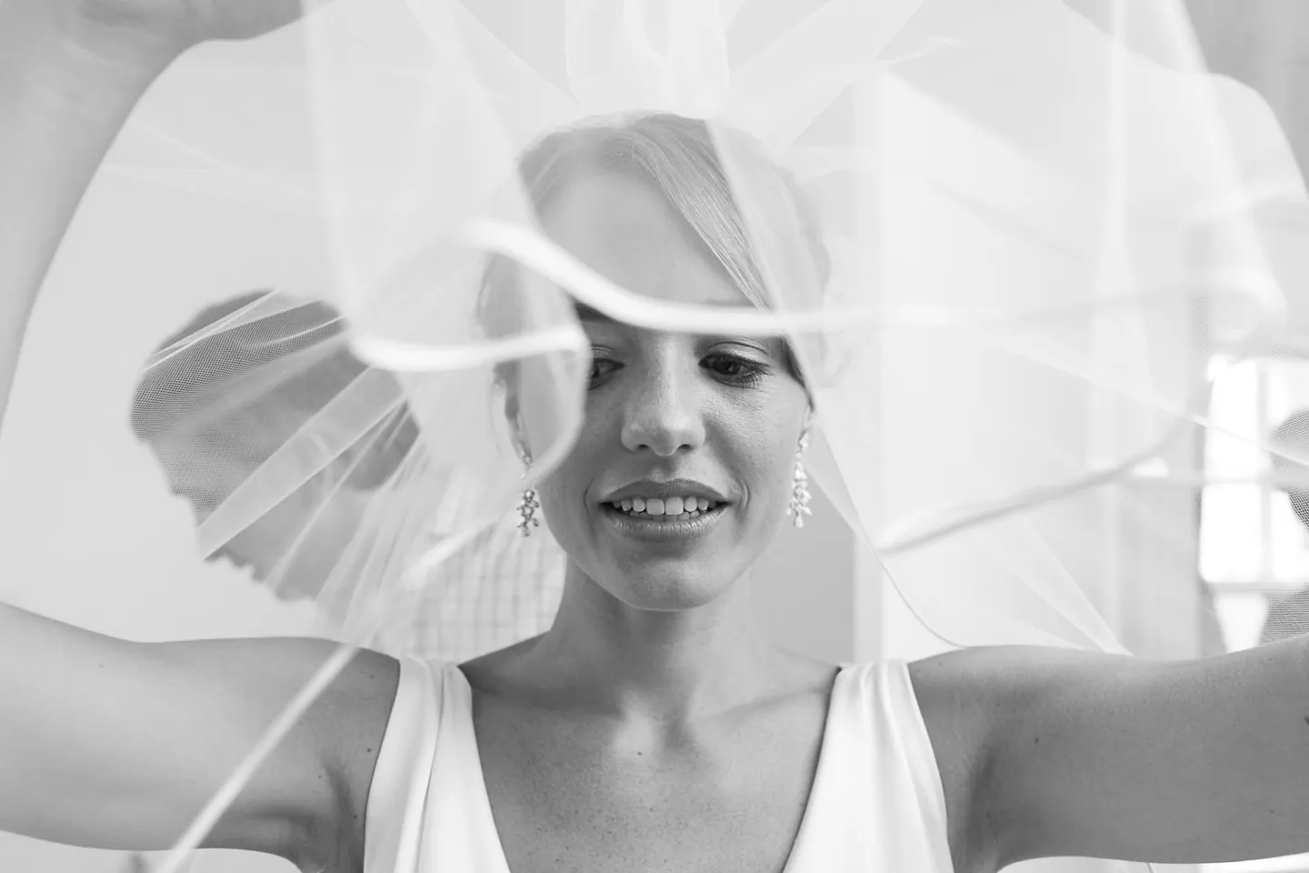 Black and white frame of the bride smiling as her veil floats around her face