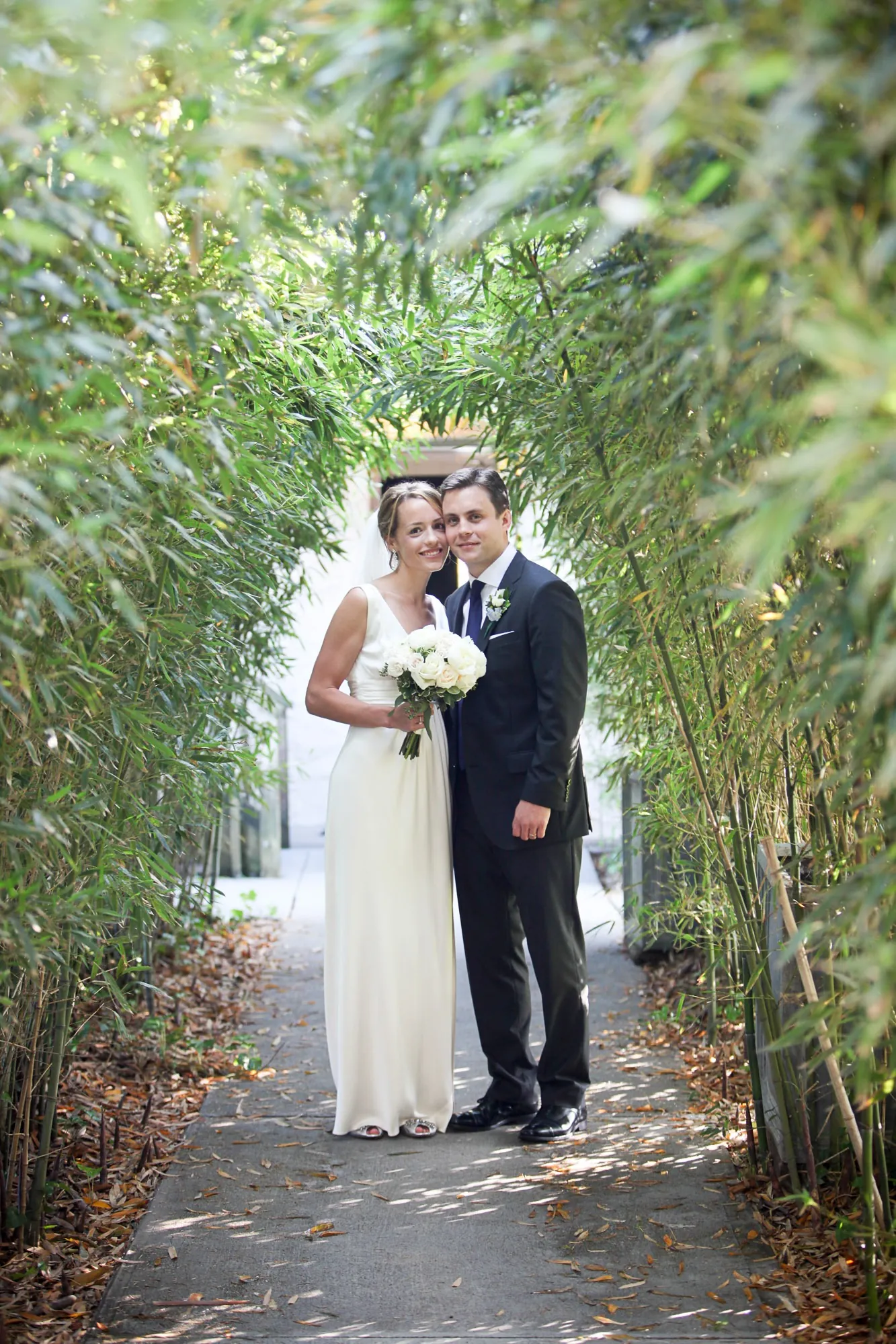 Kyla and Caley kiss at the end of the bamboo aisle, framed by green stalks