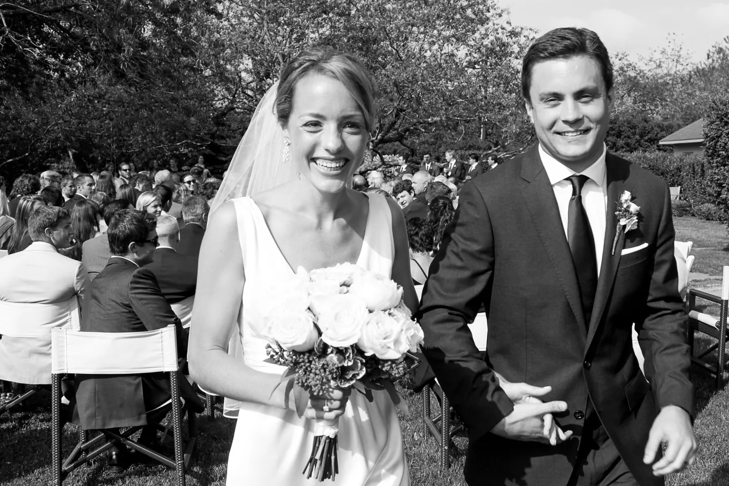 Black and white recessional, the couple smiling as seated guests turn to watch