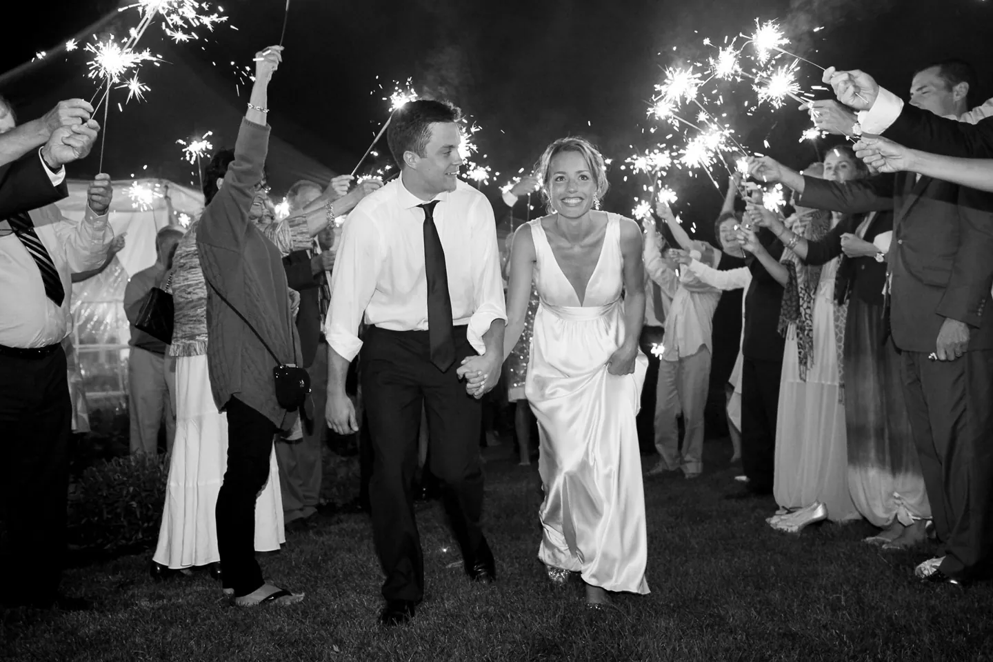 Black and white sparkler exit, Kyla and Caley running hand in hand through a tunnel of guests