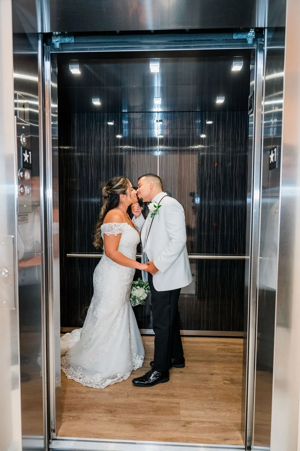 Leslie and Miguel kiss inside a steel elevator as the doors stand open