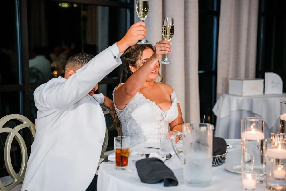 Leslie and Miguel raise champagne flutes high at the candlelit head table