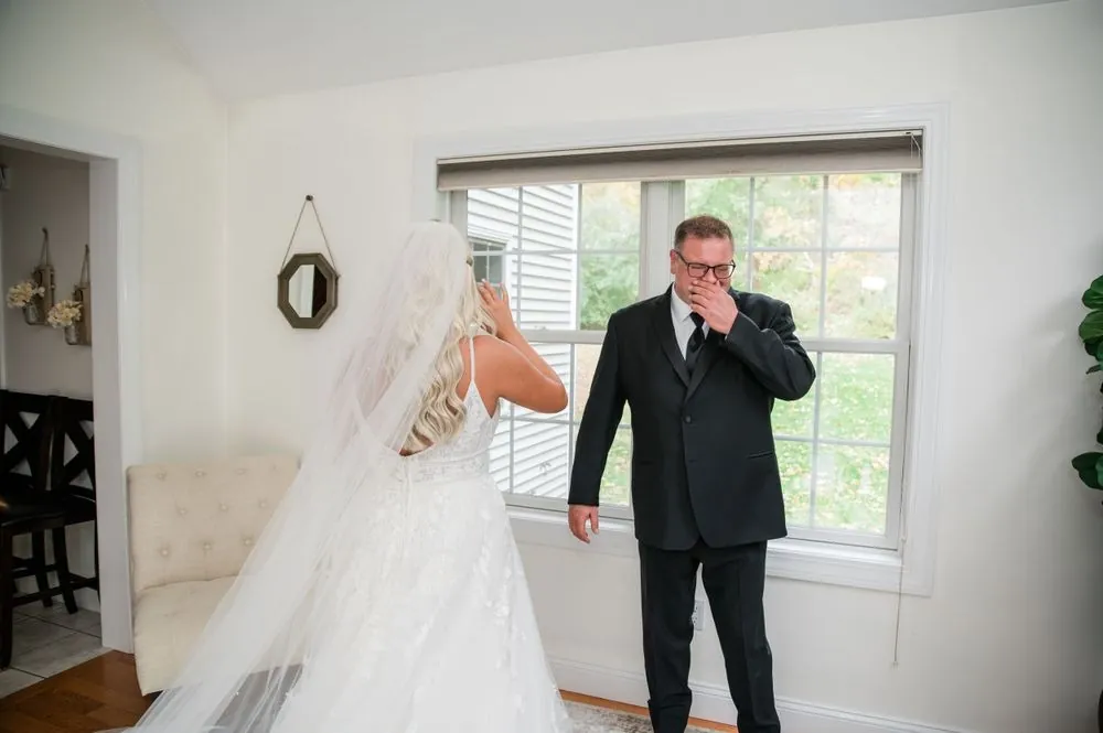 The older man covers his mouth with his hand as he turns to see the bride