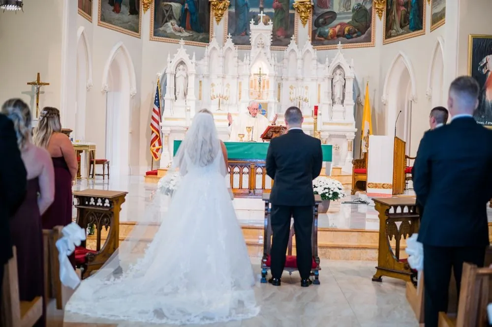 The bride and groom stand at a white marble altar as the church looks on