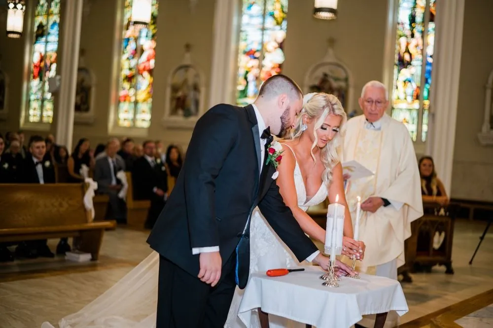 Lexy and Dillon light a unity candle together as the priest reads beside them
