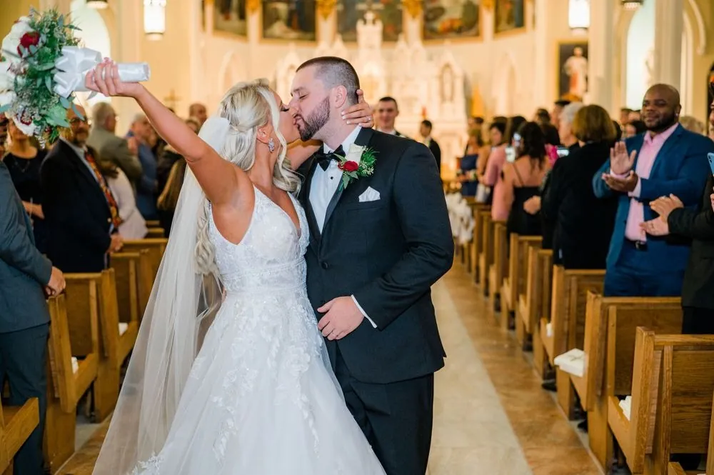 Lexy and Dillon kiss in the aisle as guests cheer and raise their hands
