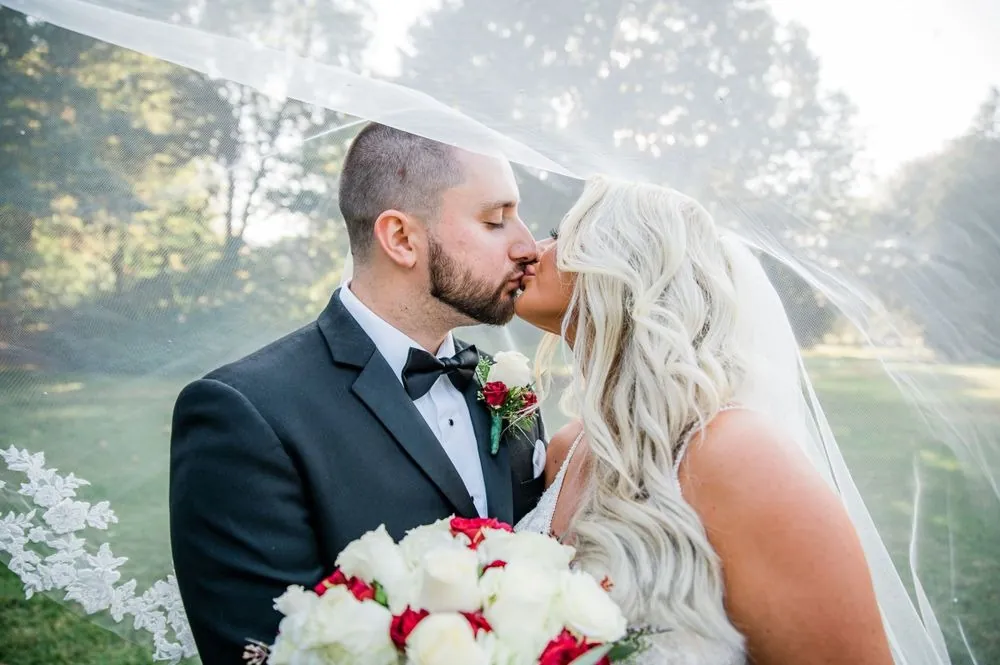Lexy and Dillon kiss under her veil in warm late afternoon light