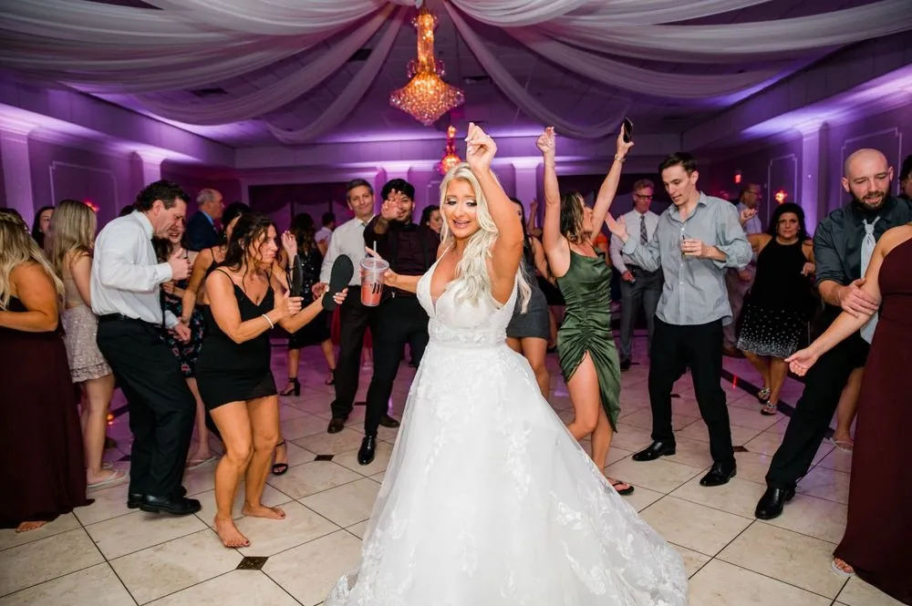 The bride dances in the middle of a crowded floor under purple uplighting