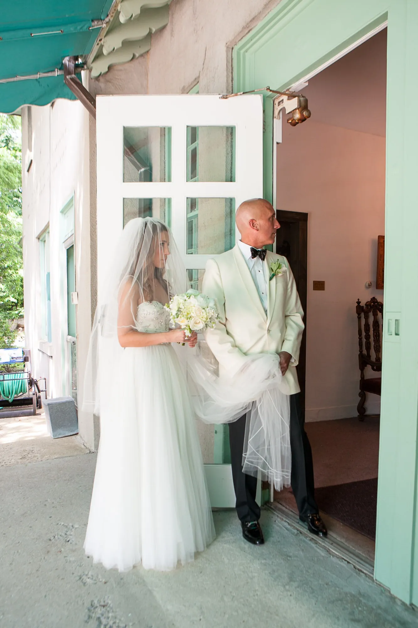 Maddie and Dave stand in a mint green doorway on a porch