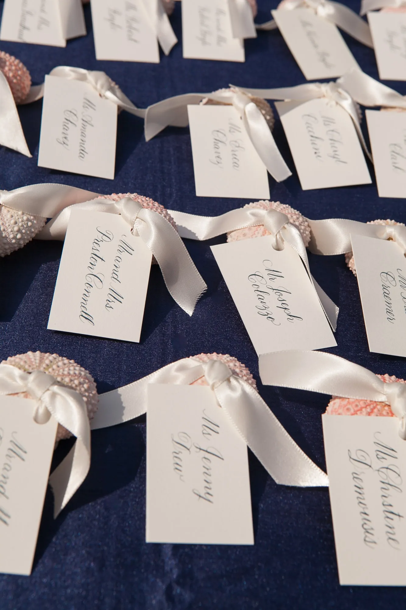 Handwritten escort cards tied in rows across a navy tablecloth