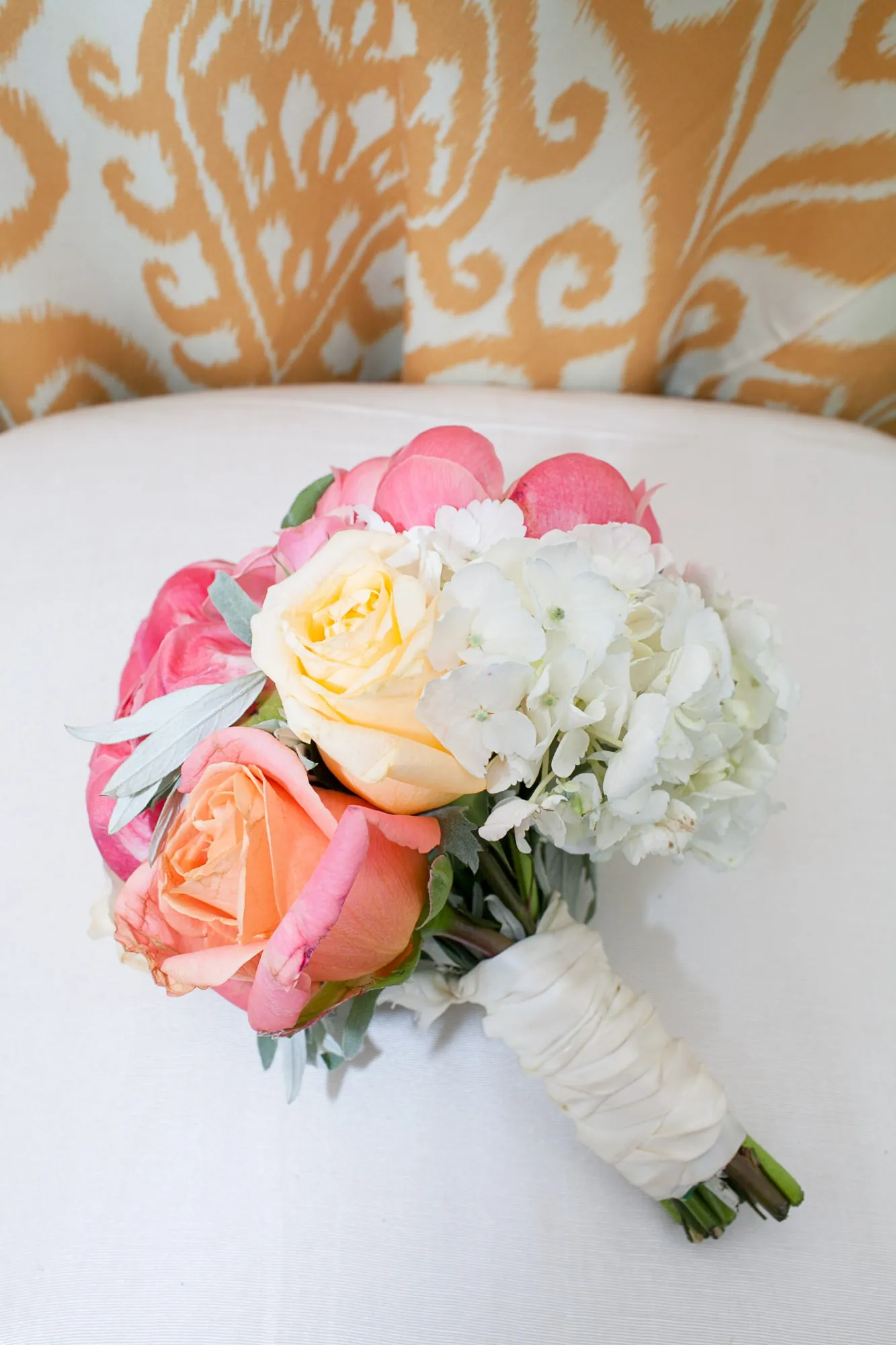 A bouquet of peach roses and white hydrangea laid on a patterned cloth