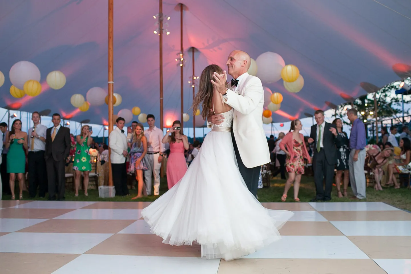 Maddie and Dave spin through their first dance on a checkered floor ringed by guests