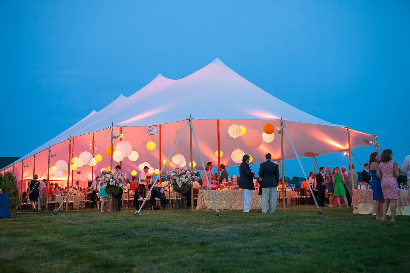 The sailcloth tent lit pink from inside against a deep blue evening sky