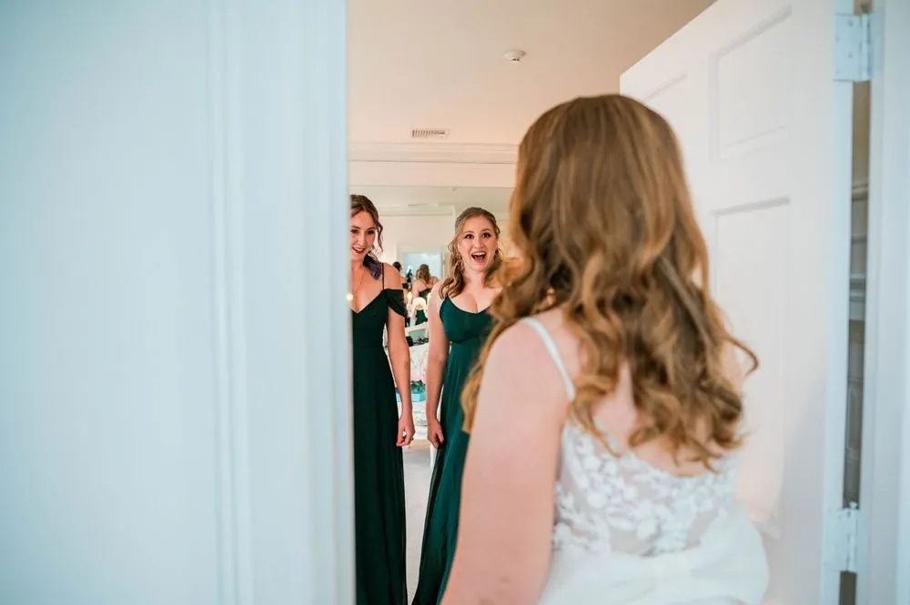 Bridesmaids in green gowns turn to see the bride in her dress for the first time