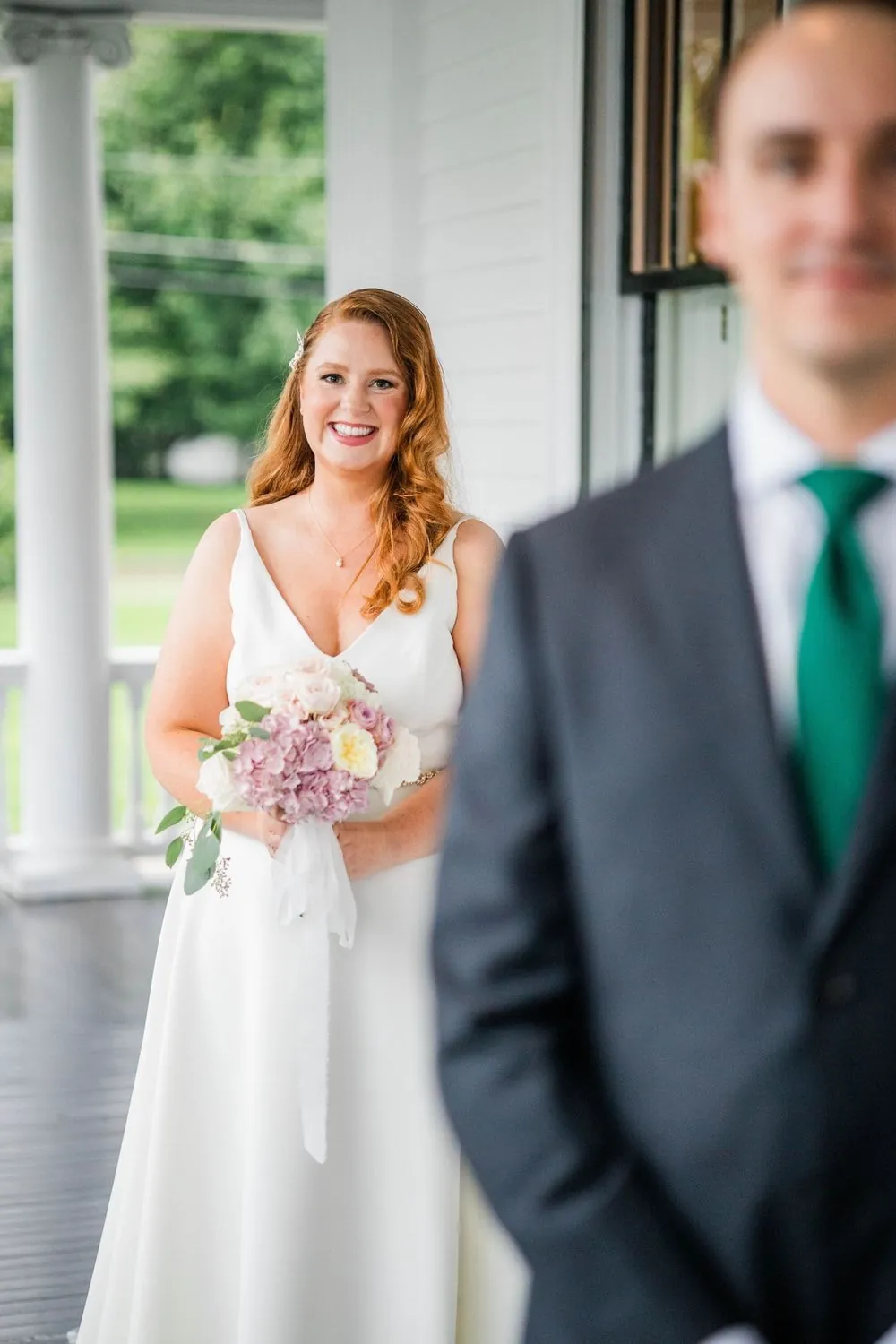 The groom turns to face the bride on the covered porch during their first look