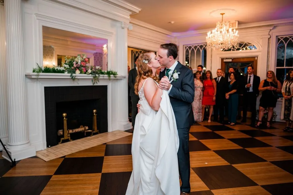 The couple's first dance on a black and white checkerboard floor by the fireplace