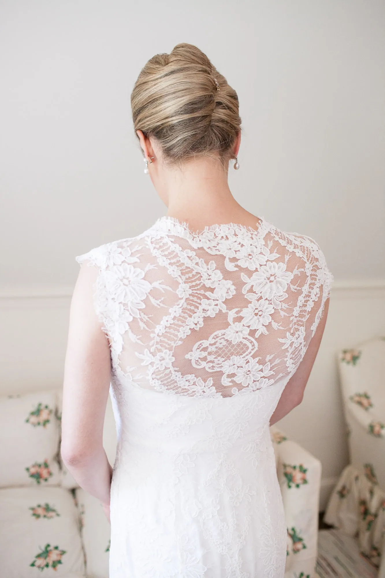 The lace back of the bride's gown, her hair pinned up in a low twist