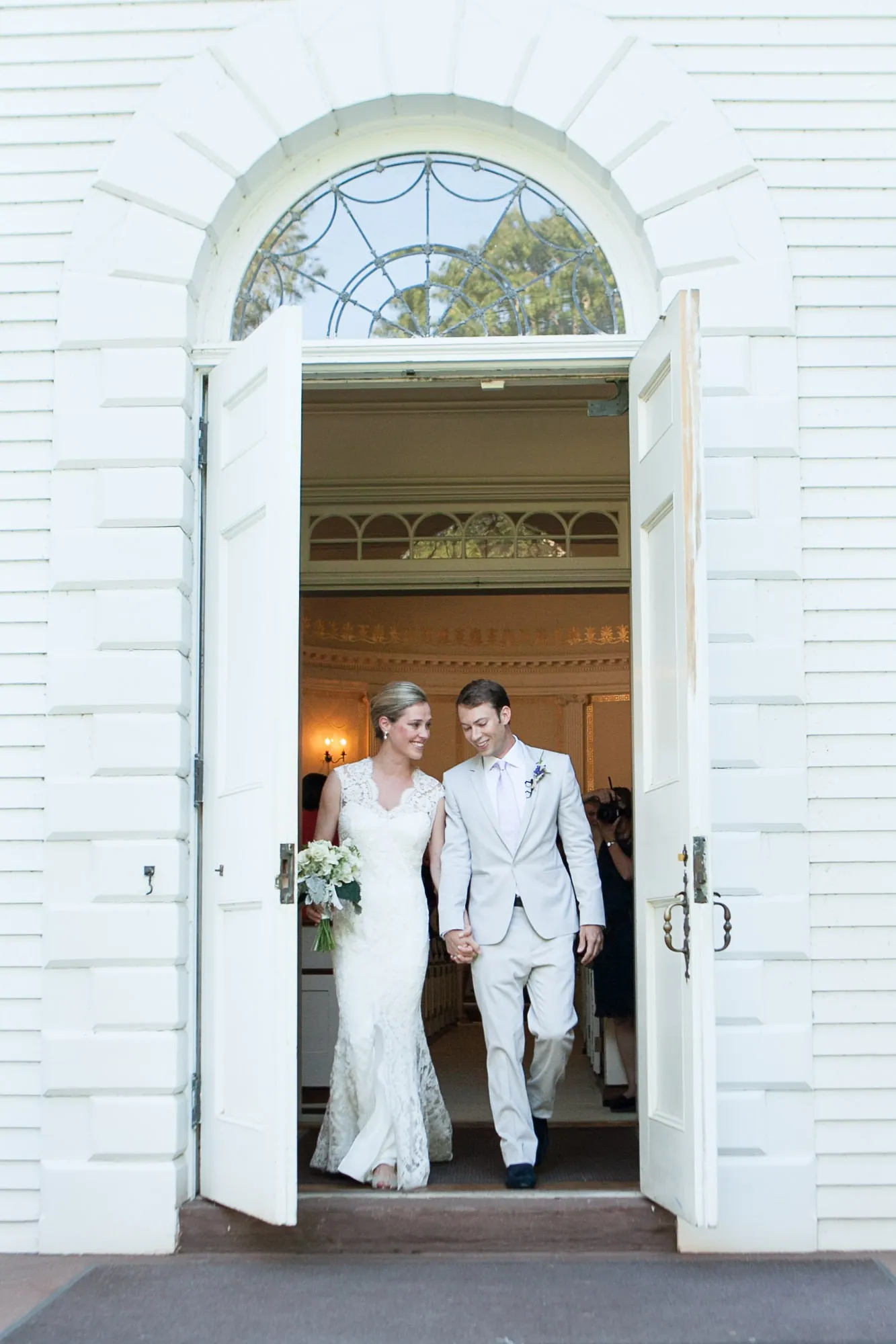 Marina and James step out through the tall white doors of the church