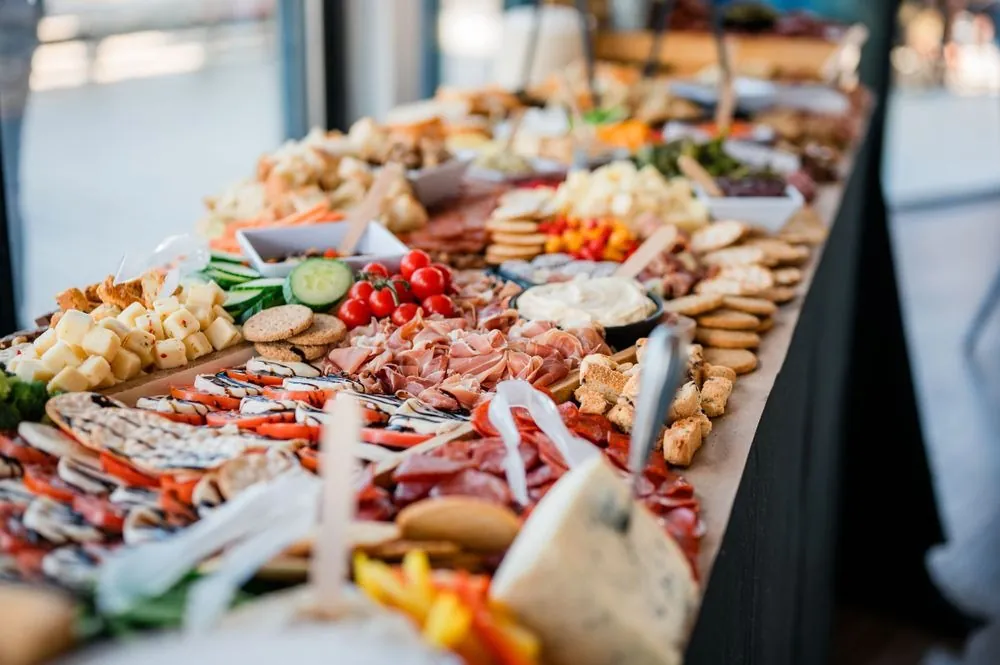 Long charcuterie spread of cured meats, cheeses, crackers, and fruit on the buffet