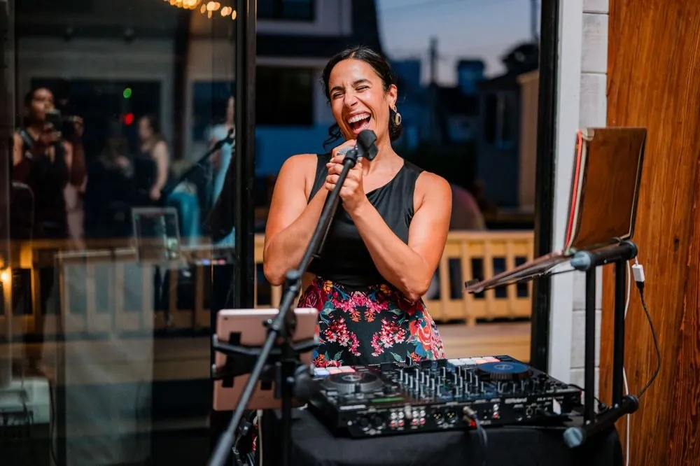 Singer laughs into a microphone behind her DJ table inside the pavilion
