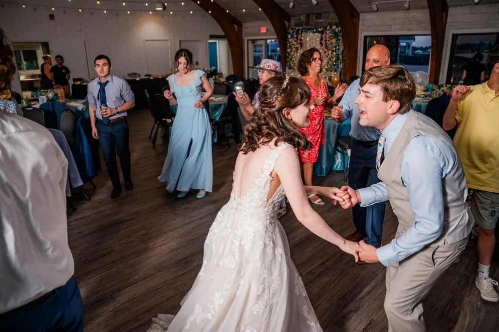 Groom bows low to the bride on the dance floor as guests dance around them