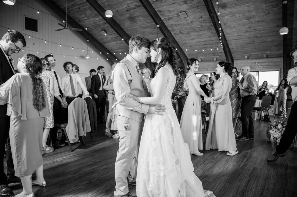 Black and white frame of a slow dance surrounded by guests on the pavilion floor
