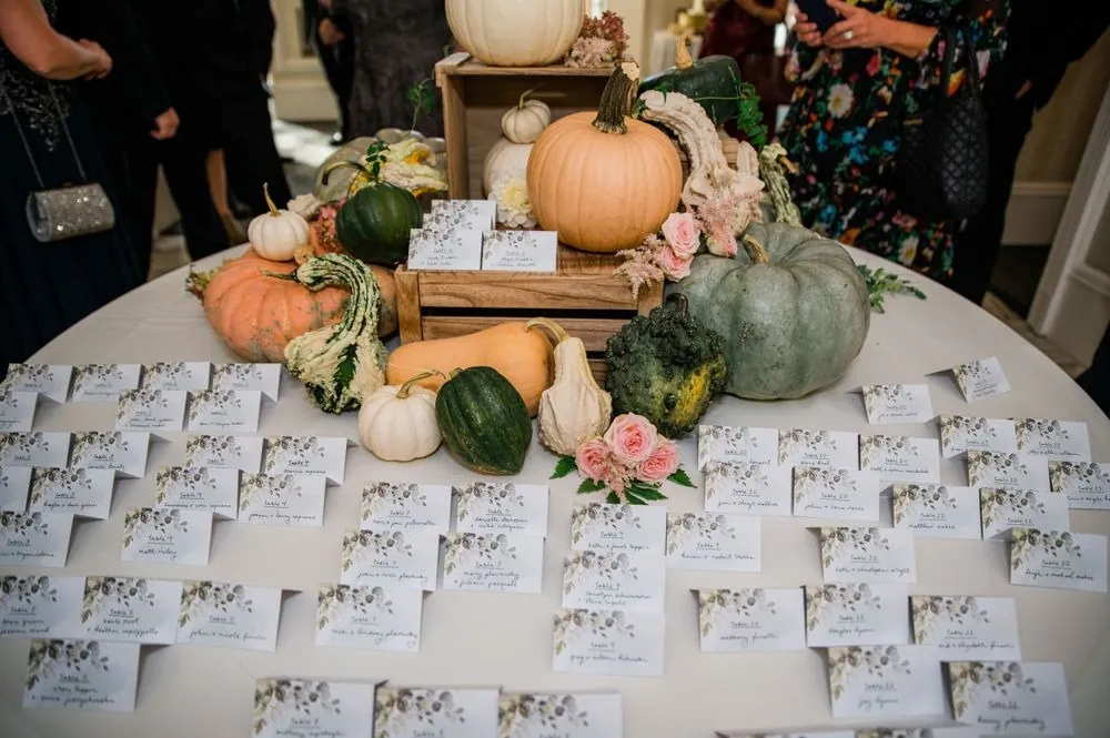 Escort cards arranged around pumpkins and gourds on a round table